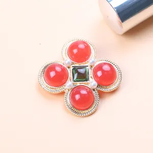 Close-up of vintage Baroque brooch with red stones, pearls, and gold-toned rope detail