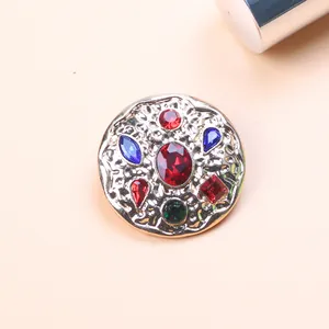 Close-up of vintage Baroque brooch with colorful gemstones and hammered metal texture.