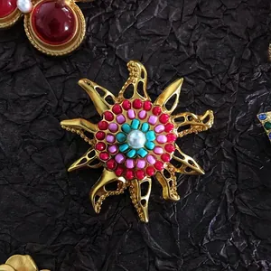 Detailed macro shot of vintage gold sun goddess brooch with colorful beads and pearl