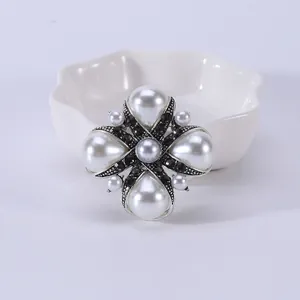 Close-up van vintage paleisstijl kruisspeld met witte parels en zwarte strass-stenen