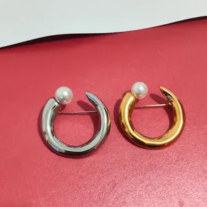 Close-up of elegant gold and silver C-shaped metal brooches with white pearl details