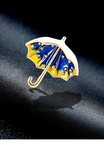 Detailed macro shot of a gold-toned starry sky umbrella brooch with enamel inlay.