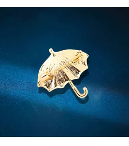 Close-up macro view of the back of a gold umbrella brooch showing the pin mechanism