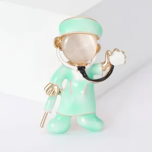 Detail of a cartoon doctor brooch with cat's eye stone and green scrubs.