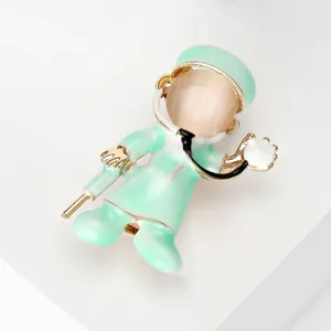 Close-up detail of a cartoon doctor brooch featuring a green uniform and cat eye stone