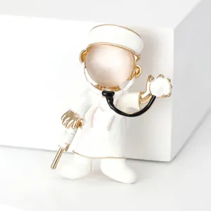 Detailed view of a cartoon doctor brooch featuring white enamel and a cat's eye stone.