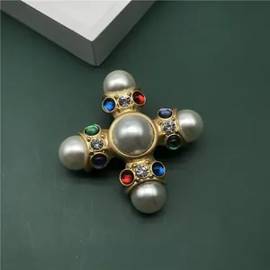 Detailed view of vintage Baroque gold cross brooch with pearls and colorful crystals