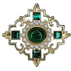 Detail of a vintage Baroque brooch with green gemstones and pearls in a gold openwork design