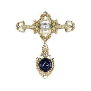 Close-up detail of vintage gold Baroque cross brooch with pearl and dark gemstone inlay