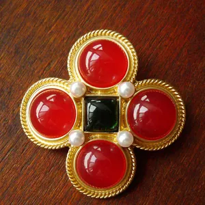 Detailed view of a vintage gold cross brooch with red and green stones