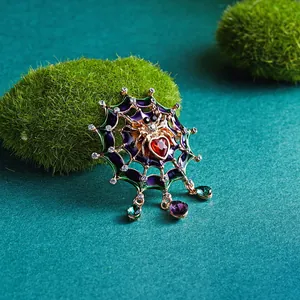 Detailed view of an ornate spider web brooch with enamel and heart-shaped red stone.
