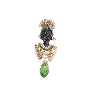 Vue détaillée de la broche exotique avec visage en émail noir et pendentif en cristal vert