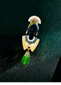Exotic vintage black woman head brooch with ornate headpiece and large green teardrop crystal