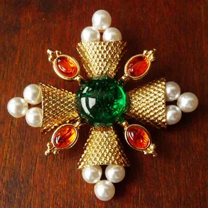 Vintage palace style brooch with green crystal and white pearls on wood background