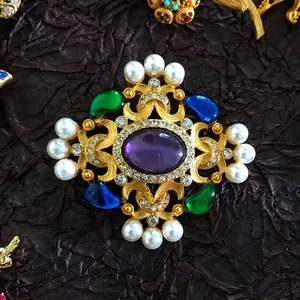 Detailed view of a vintage baroque brooch with purple gem, colorful stones and pearls