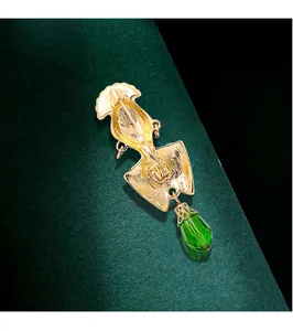 Detailed back view of a vintage exotic gold brooch featuring a green crystal teardrop