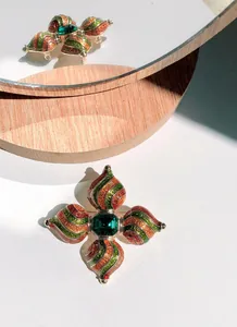 Detailopname van een barokke kruisbroche met groen emaille en centrale edelsteen.