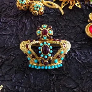 Detailed view of a vintage Baroque crown brooch with red gems and turquoise beads