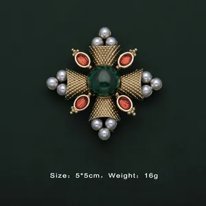 Detailed view of vintage Baroque brooch with a green central gemstone and pearls