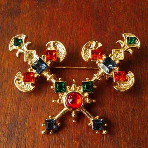 Detailed view of a vintage royal style brooch with multi-colored gemstones on wood
