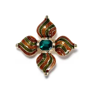 Detailweergave van barokke kruisbroche met groene edelsteen en emaille wervelingen