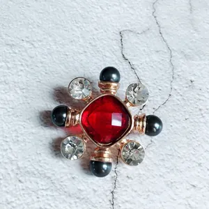 Detail view showing a luxury baroque brooch with red central gem and black pearls