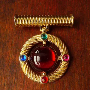 Detailed view of a vintage royal style gold brooch set with vibrant colorful gemstones