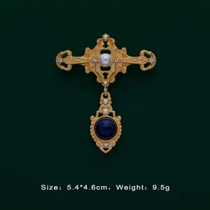 Detailed macro view of a Baroque vintage gold brooch with pearls and blue gemstone.