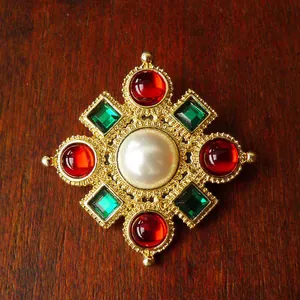 Detailed macro shot of vintage court style brooch with pearl and colorful gems on wood