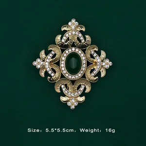 Detailed view of Baroque gold brooch with green gemstone and rhinestones, dimensions shown