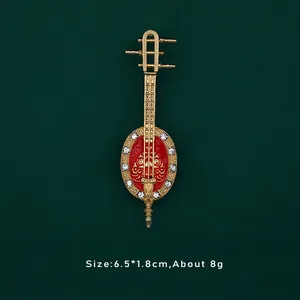 Dettaglio di una spilla strumento musicale barocco vintage con smalto rosso e strass