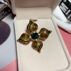 Detailed view of a vintage baroque brooch with green gemstone and enamel inlay