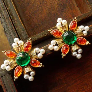 Detailed close-up of vintage palace style flower brooch with green and orange gems and pearls