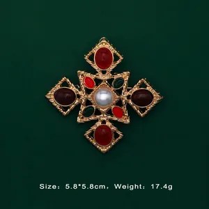 Detail view of baroque vintage gold cross brooch with colorful gemstones and pearl