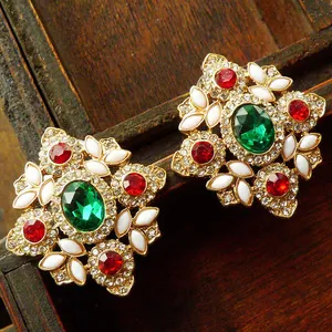 Detailed macro view of vintage palace style brooch featuring colorful green and red gemstones