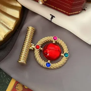Detail view of a luxury vintage Baroque brooch with colorful gemstones and red center