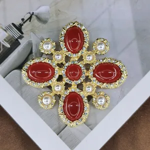 Detailed macro shot of luxury vintage baroque brooch with red stones and pearls.
