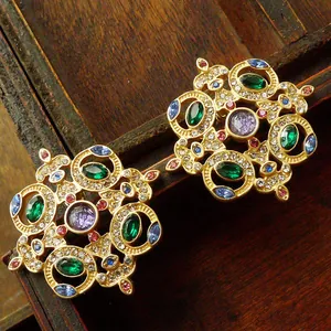 Close-up of vintage court-style brooches with colorful crystals on wood background