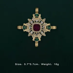 Detail of a vintage baroque gold brooch featuring red and green gemstone accents