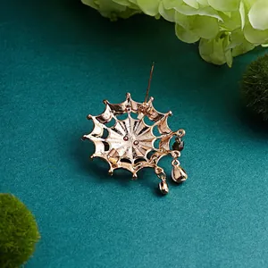 High-quality detail view of the back of a golden spider web brooch with charms.