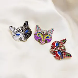 Spille vintage a maschera di volpe in smalto con strass su sfondo di stoffa crema
