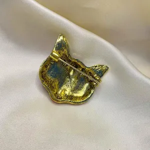 Dettaglio del retro di una spilla vintage a maschera di volpe dorata con chiusura