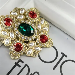 Macrodetail van een barokke vintage broche met smaragdgroene edelsteen en witte parels