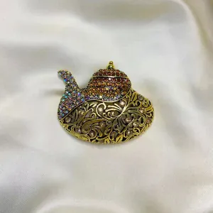 Vue détaillée d'une broche théière ornée de strass multicolores sur tissu satiné