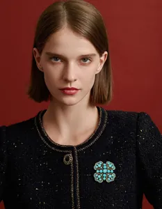Close-up of a vintage turquoise blue heart-to-heart brooch on a black tweed jacket