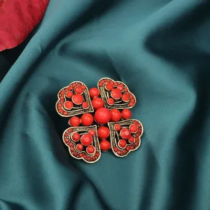 Detailed macro view of vintage style red beaded brooch pinned on dark teal satin fabric