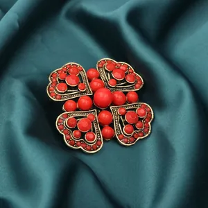 Detail view of vintage heart-shaped brooch with vibrant red beads on dark green satin