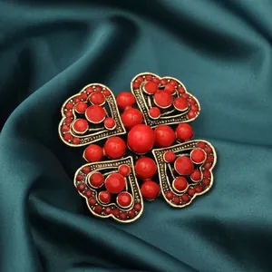 Vintage four-leaf clover brooch with red faceted beads on deep teal silk background