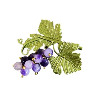 Detailed view of a vintage grape brooch with purple beads and green metallic leaves