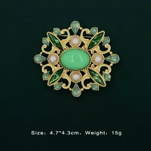 Detailed view of a vintage baroque gold brooch featuring green gemstones and pearls